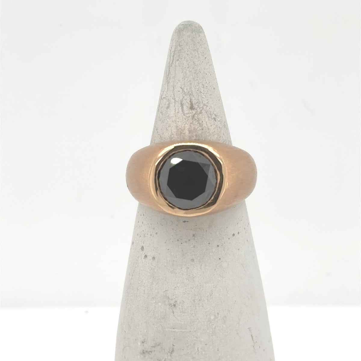 18K rose gold ring with bezel-set round black diamond on a wide band.