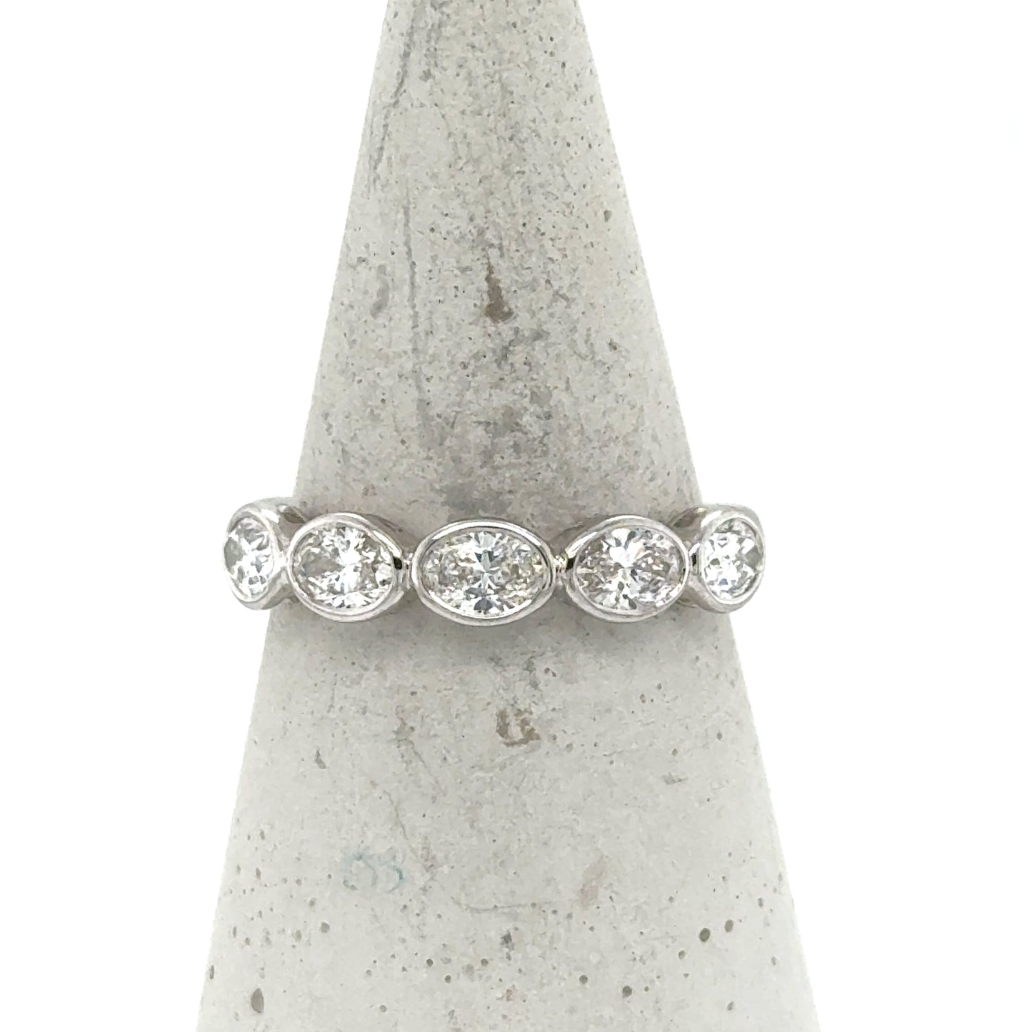 14K white gold band with five bezel-set oval and round diamonds.