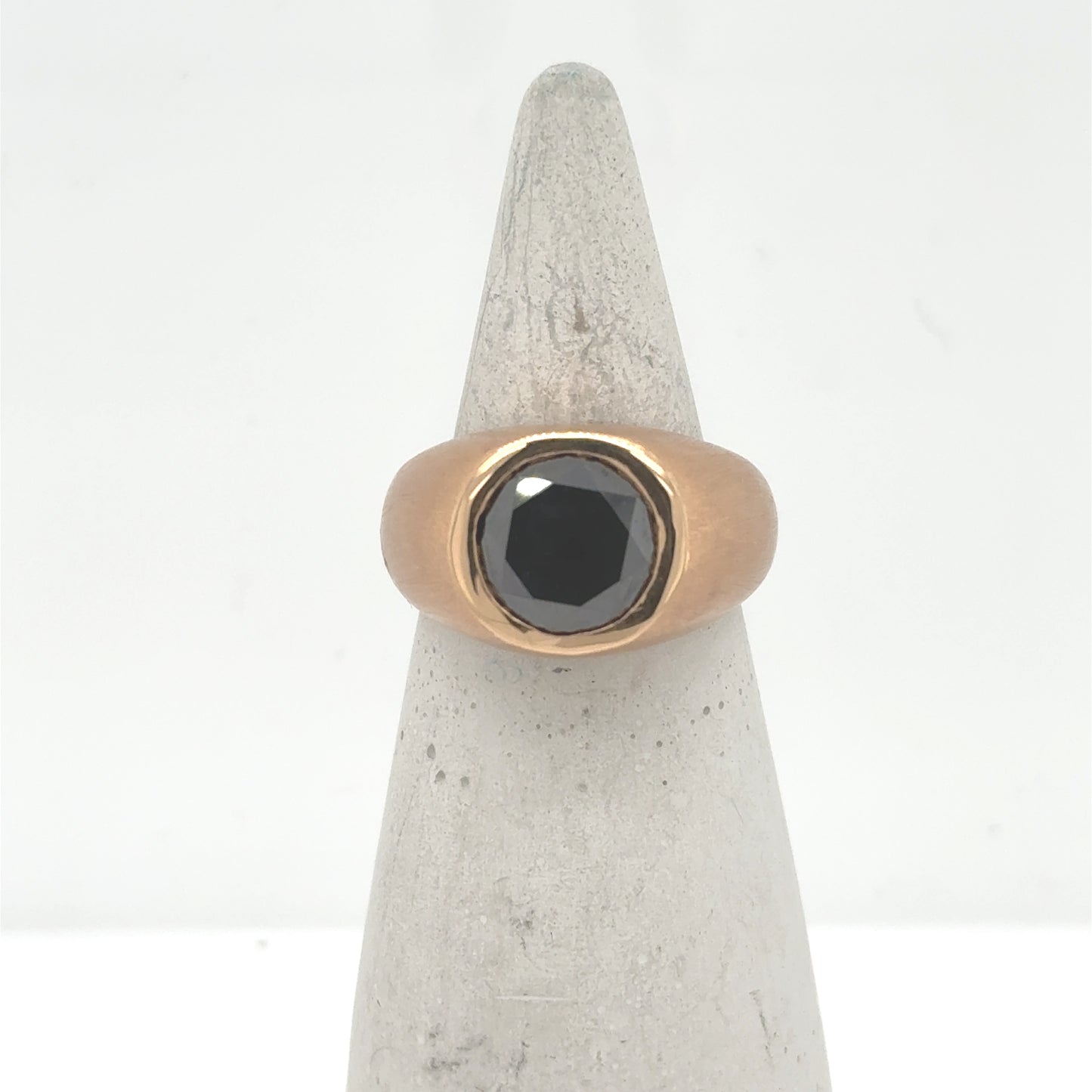 18K rose gold ring with bezel-set round black diamond on a wide band.