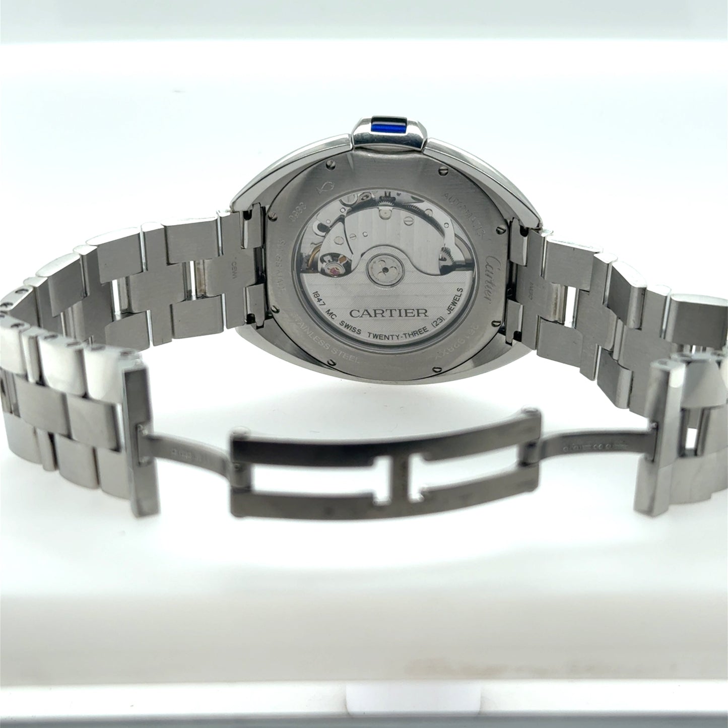 Stainless steel Cartier watch showing exhibition caseback, automatic movement, bracelet, and deployant clasp.