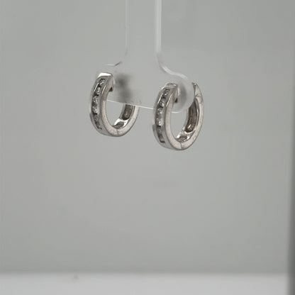 Small 14K white gold huggie hoops with channel‑set round diamonds.