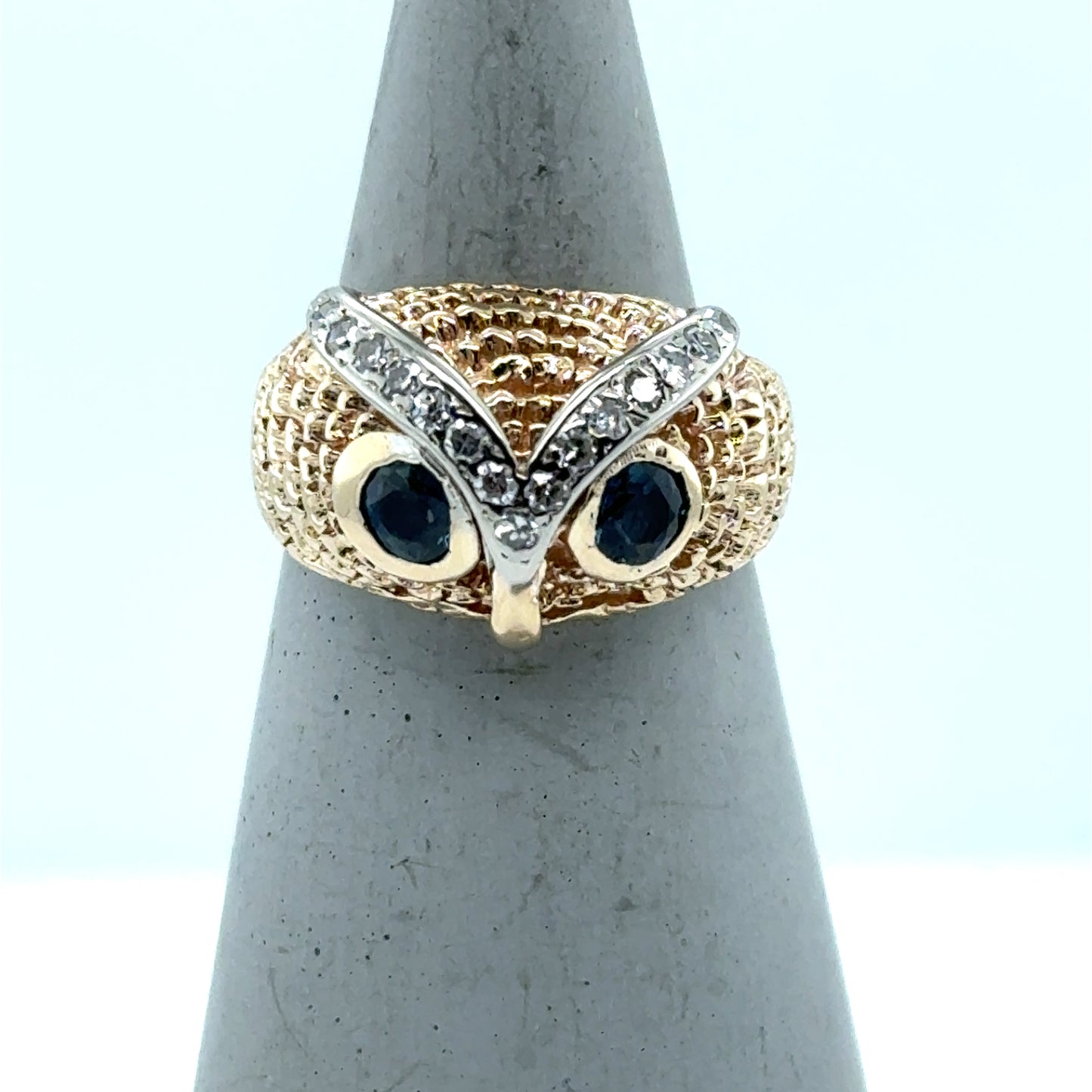 Yellow gold owl ring with blue gemstone eyes and diamond-set white gold eyebrows.