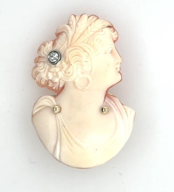 Carved shell bust cameo brooch with round diamond hair pin and gold accents.