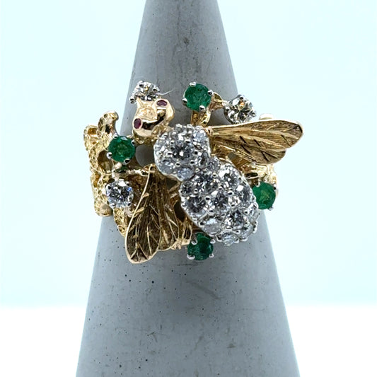 Two-tone 14K gold bee ring with diamond body, ruby eyes, emerald accents, and honeycomb band.
