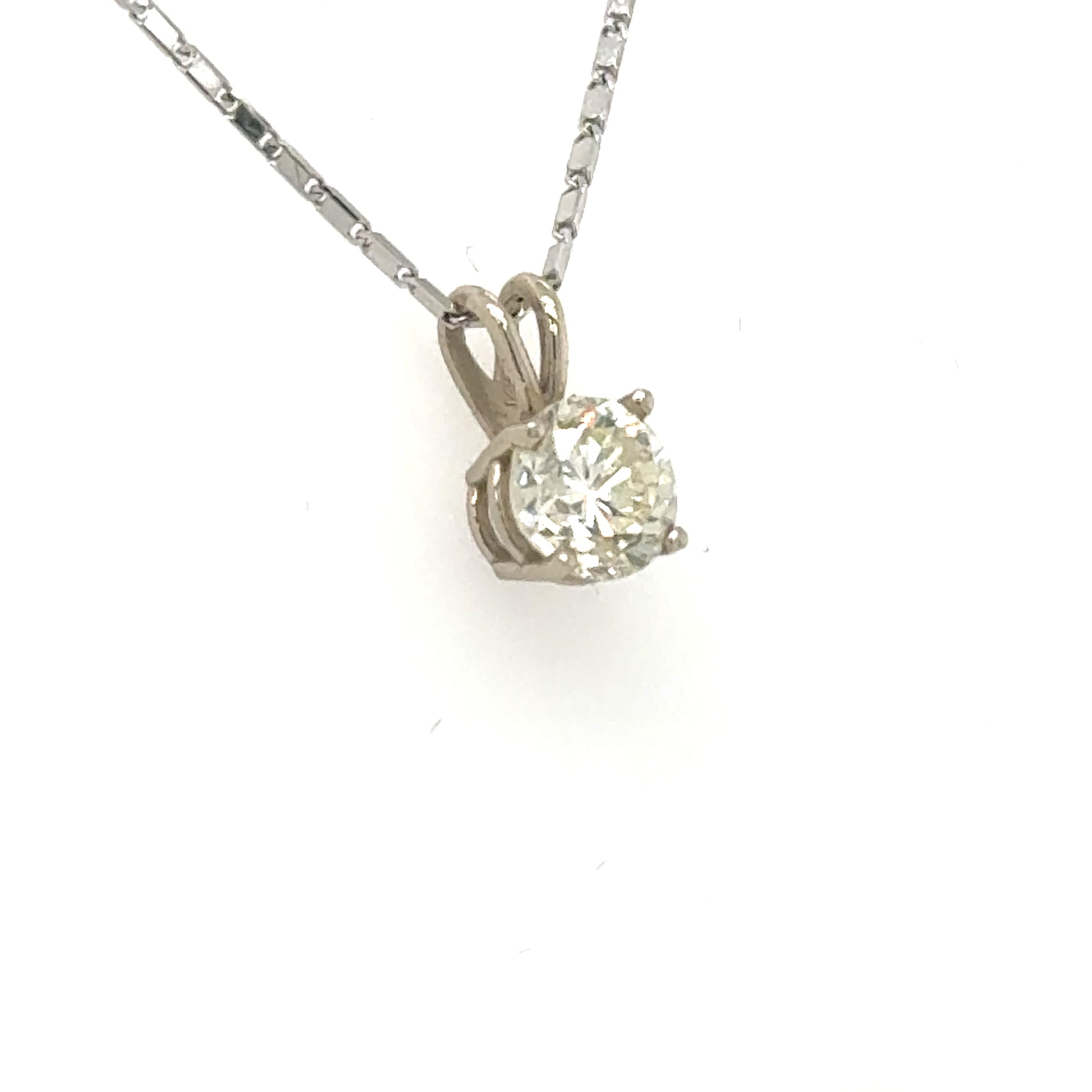 White gold solitaire pendant with round brilliant diamond in four-prong basket and rabbit-ear bail.