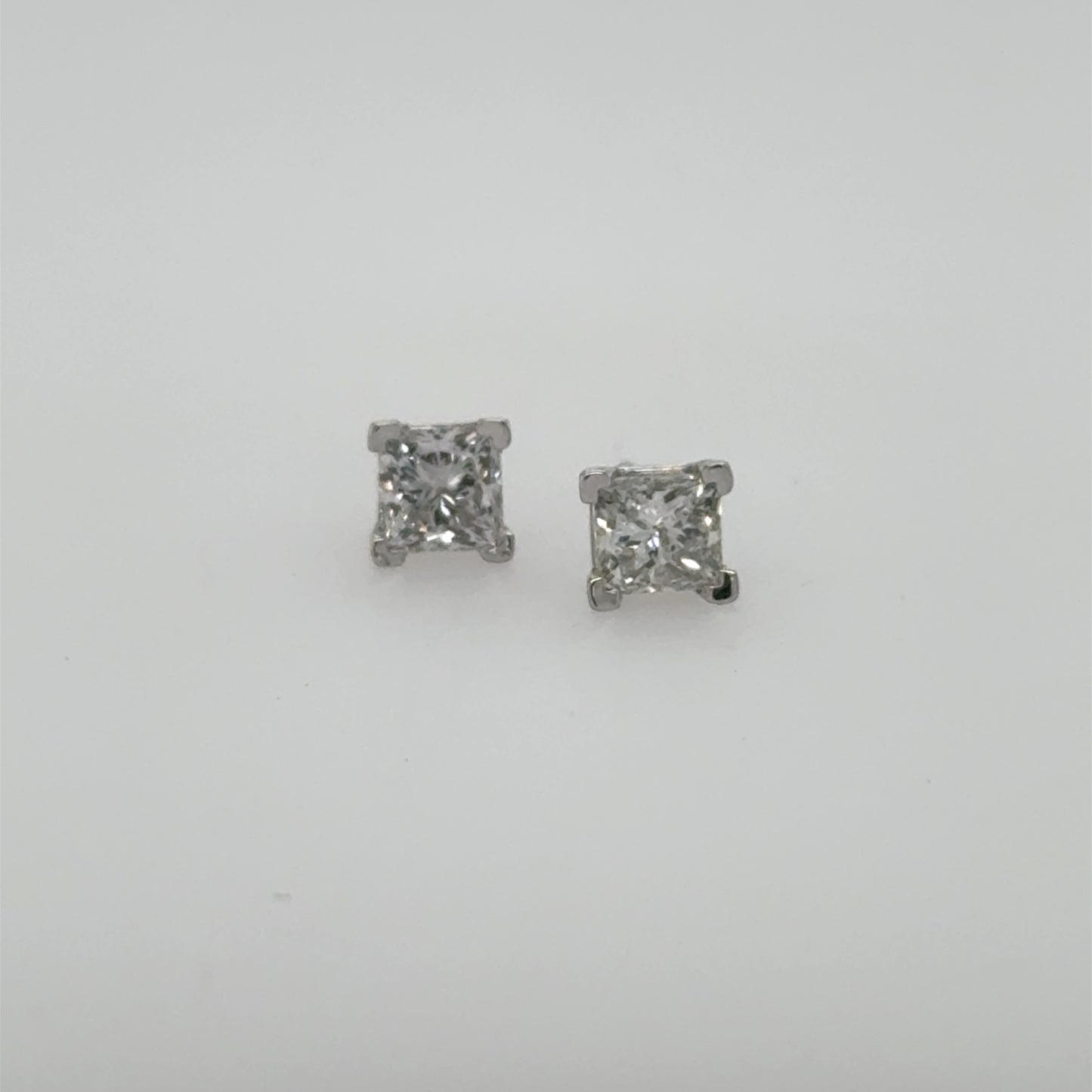 Princess-cut diamond stud earrings in white gold four-prong settings, shown front-facing.
