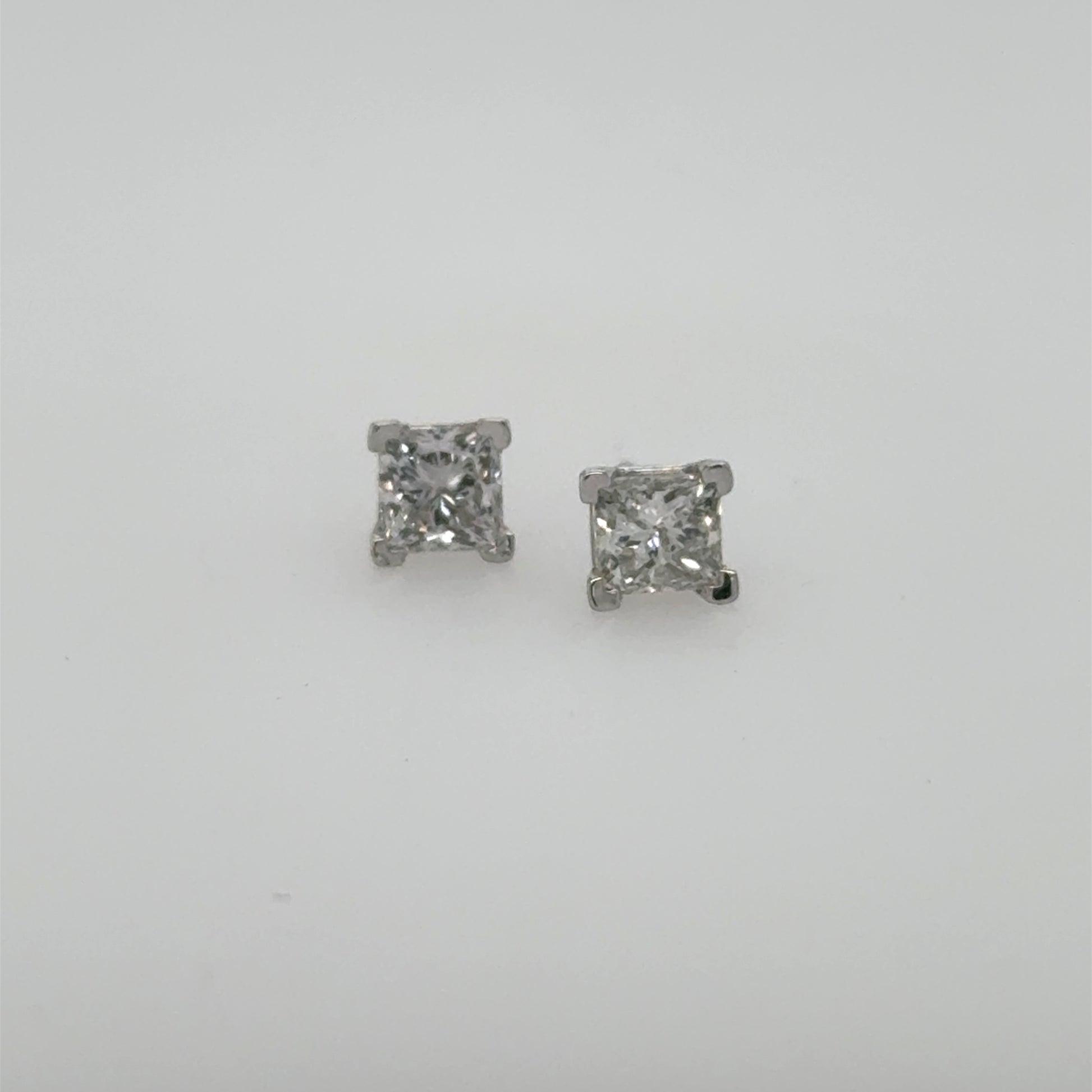 Princess-cut diamond stud earrings in white gold four-prong settings, shown front-facing.
