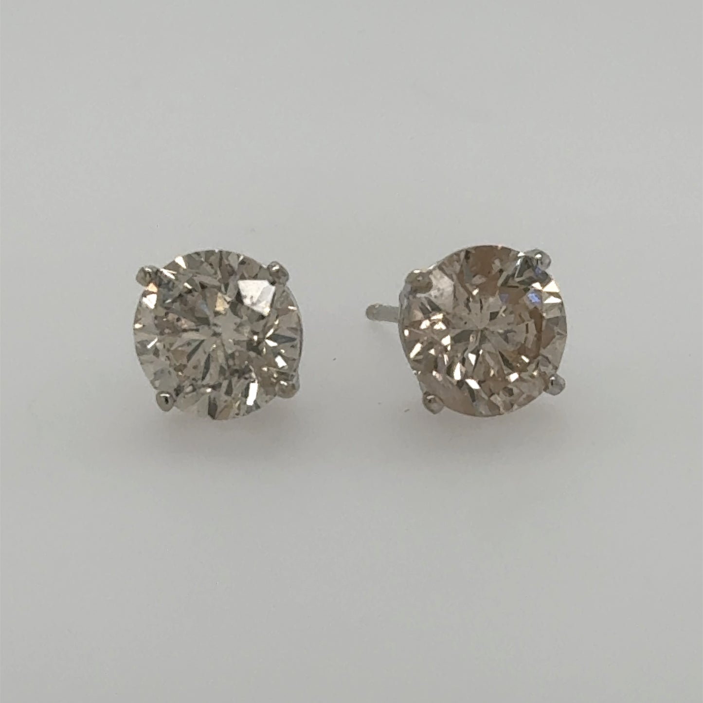Round diamond stud earrings in white gold four-prong basket settings with posts.