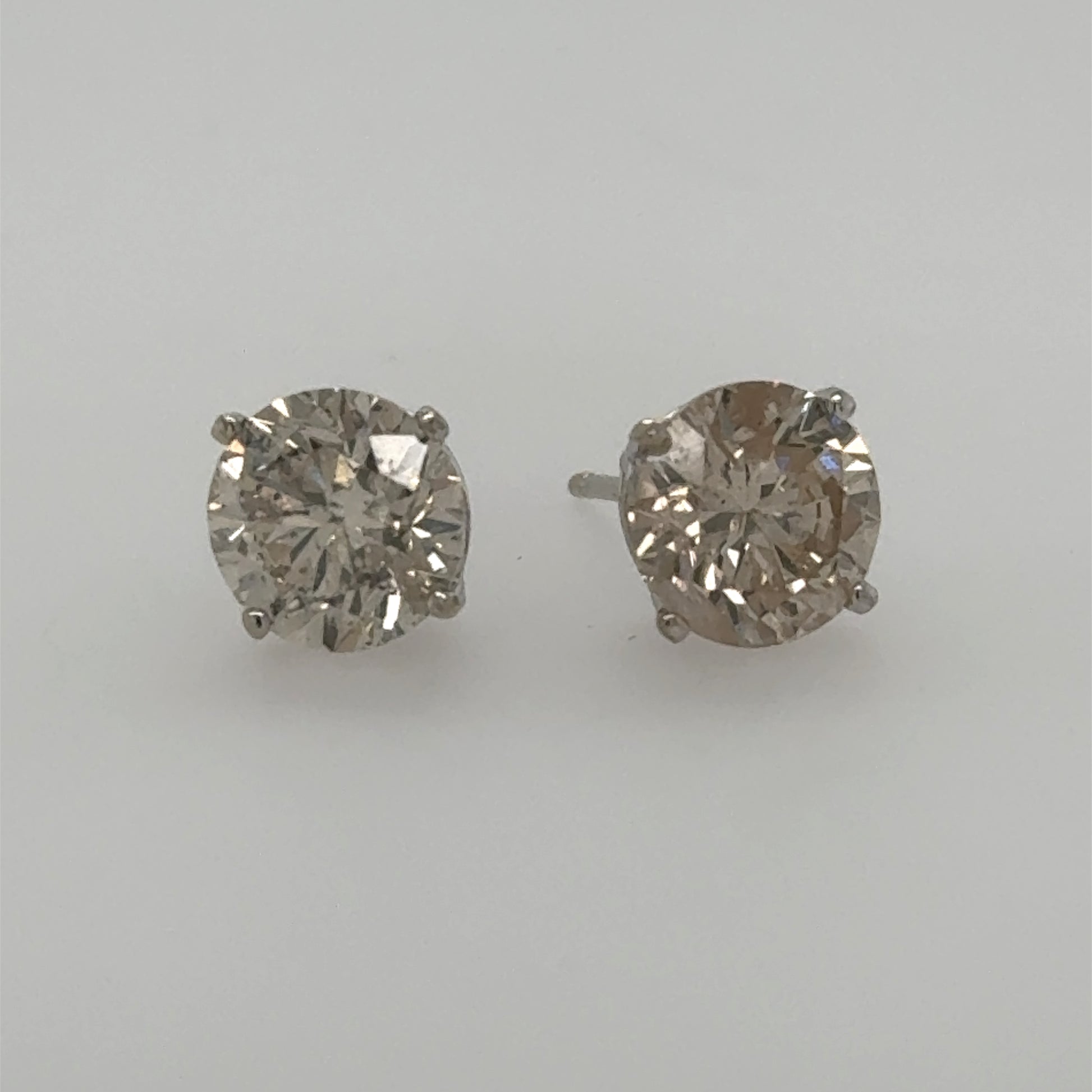 Round diamond stud earrings in white gold four-prong basket settings with posts.