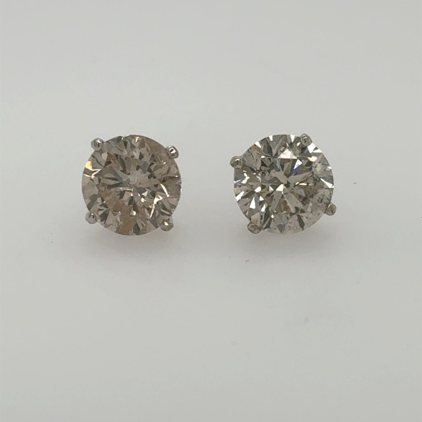 Round brilliant diamond stud earrings in white gold four-prong basket settings.