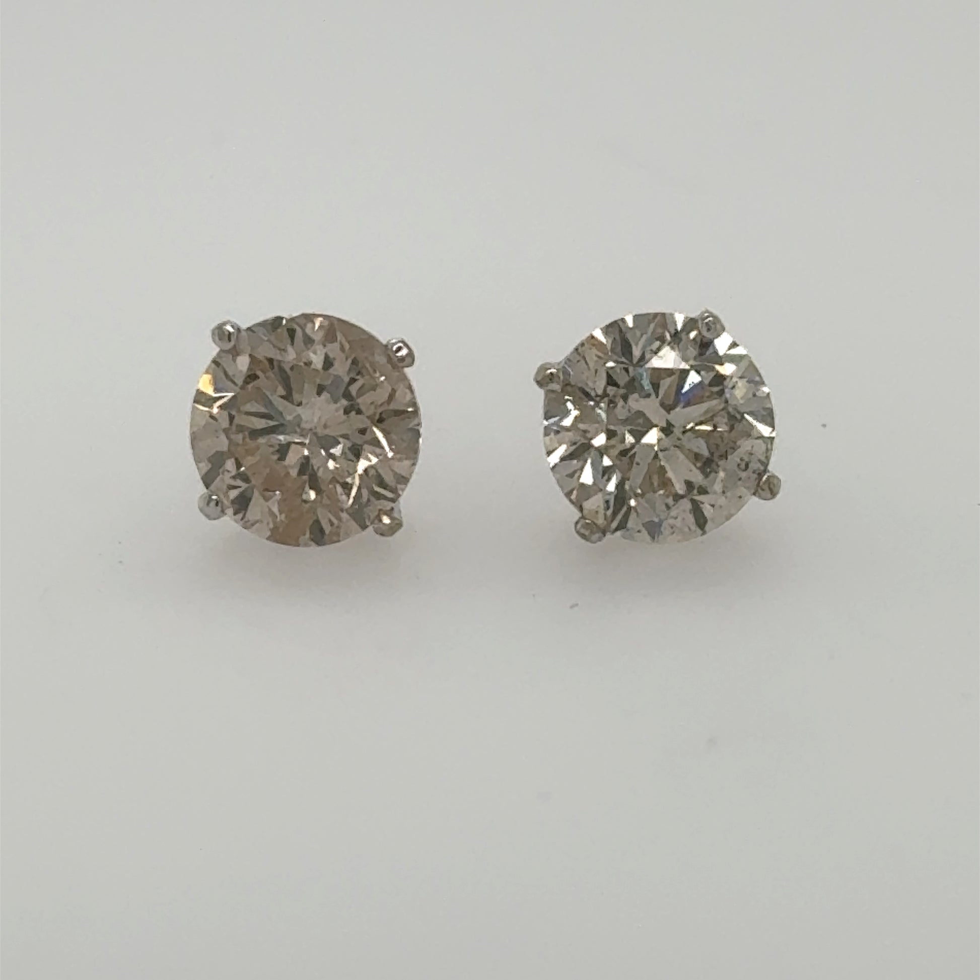 Round brilliant diamond stud earrings in white gold four-prong basket settings.