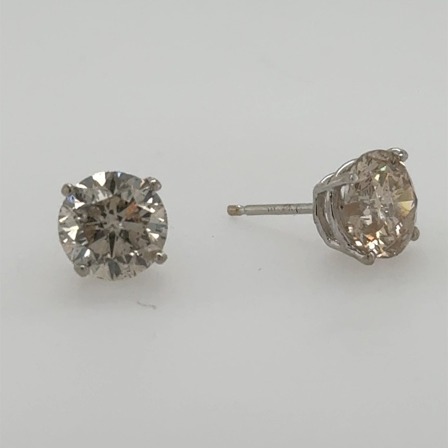 Round diamond stud earrings in 14K white gold four-prong basket settings.