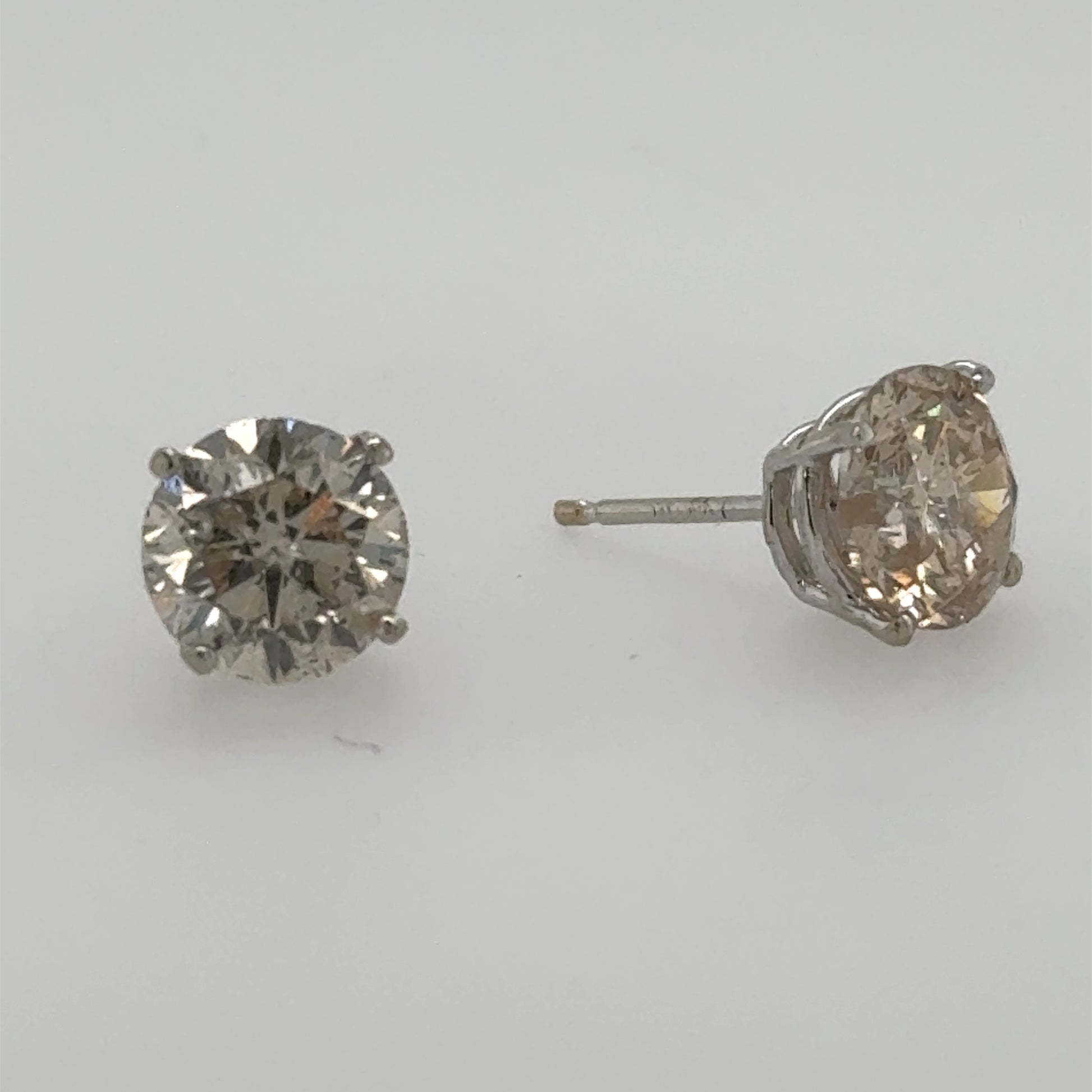 Round diamond stud earrings in 14K white gold four-prong basket settings.