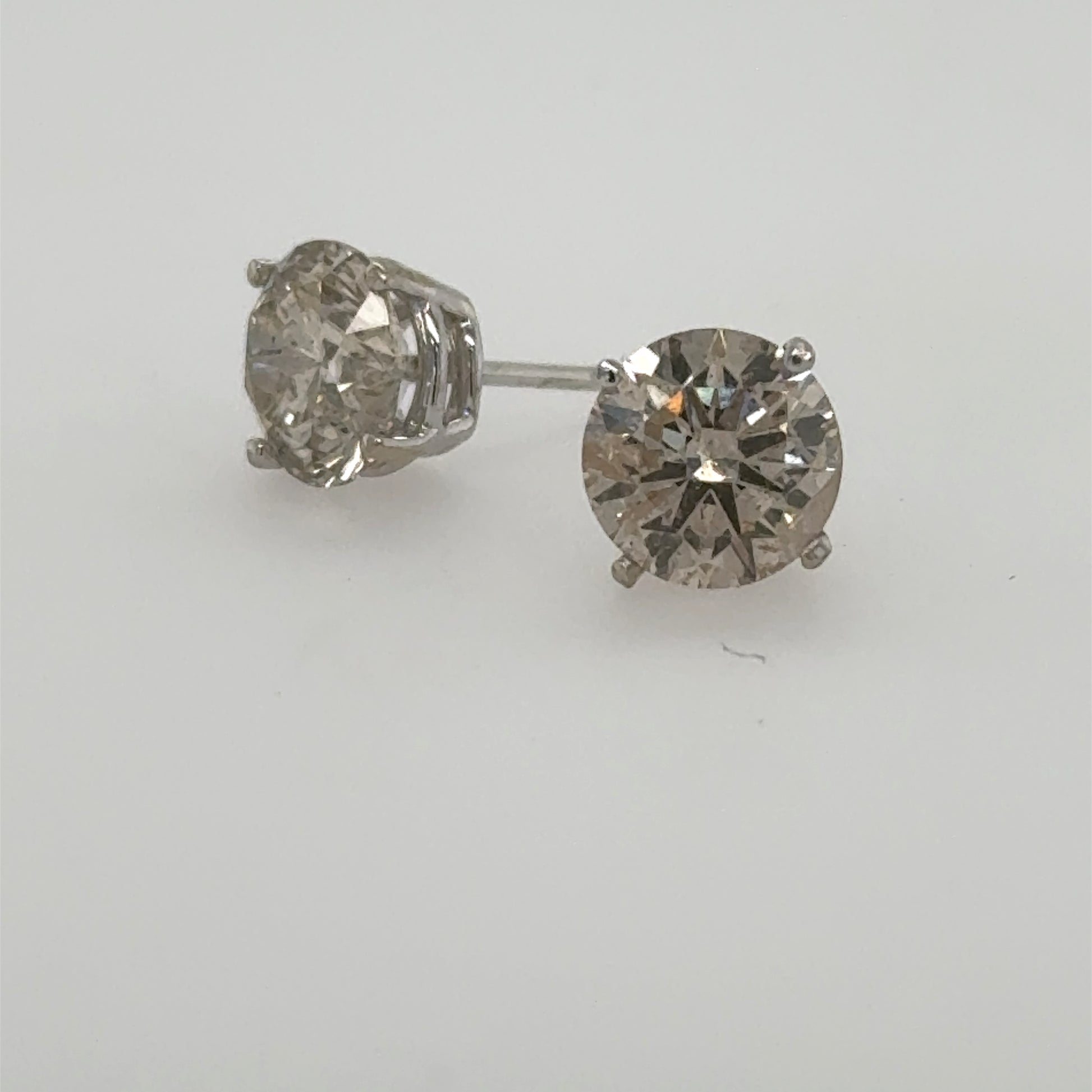Round brilliant diamond stud earrings in 14K white gold four-prong settings.
