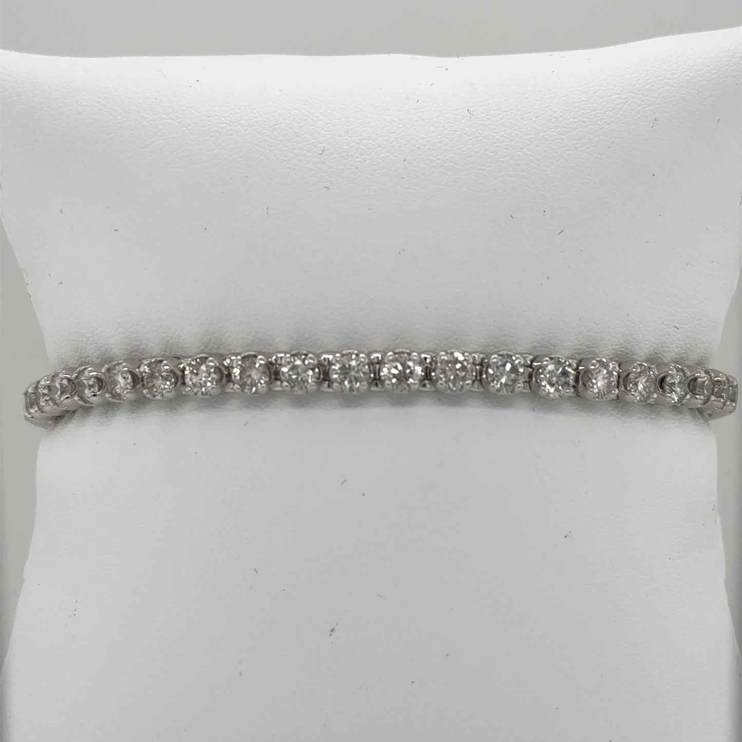 14K white gold tennis bracelet with round diamonds in prong-set straight line.