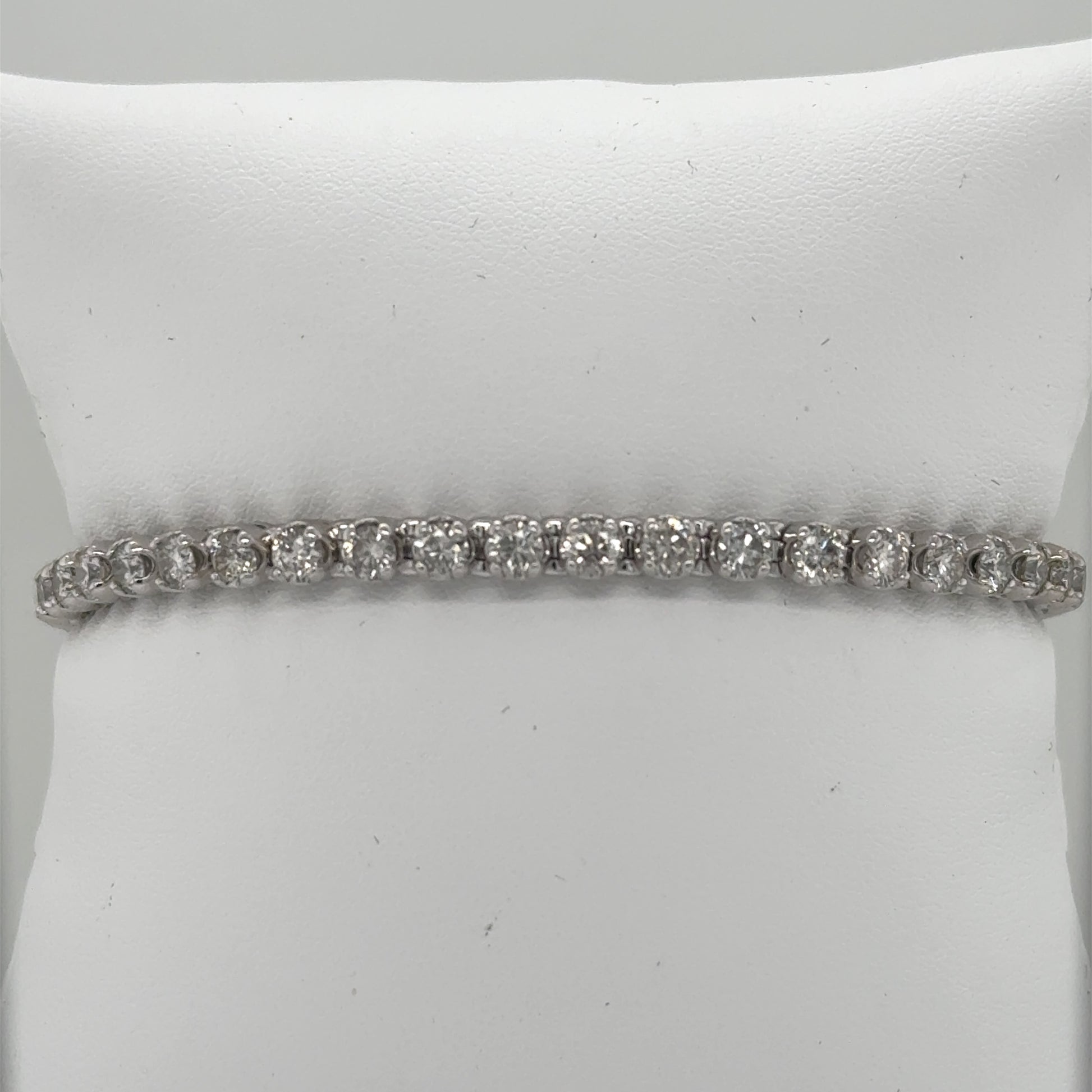 14K white gold tennis bracelet with round diamonds in prong-set straight line.