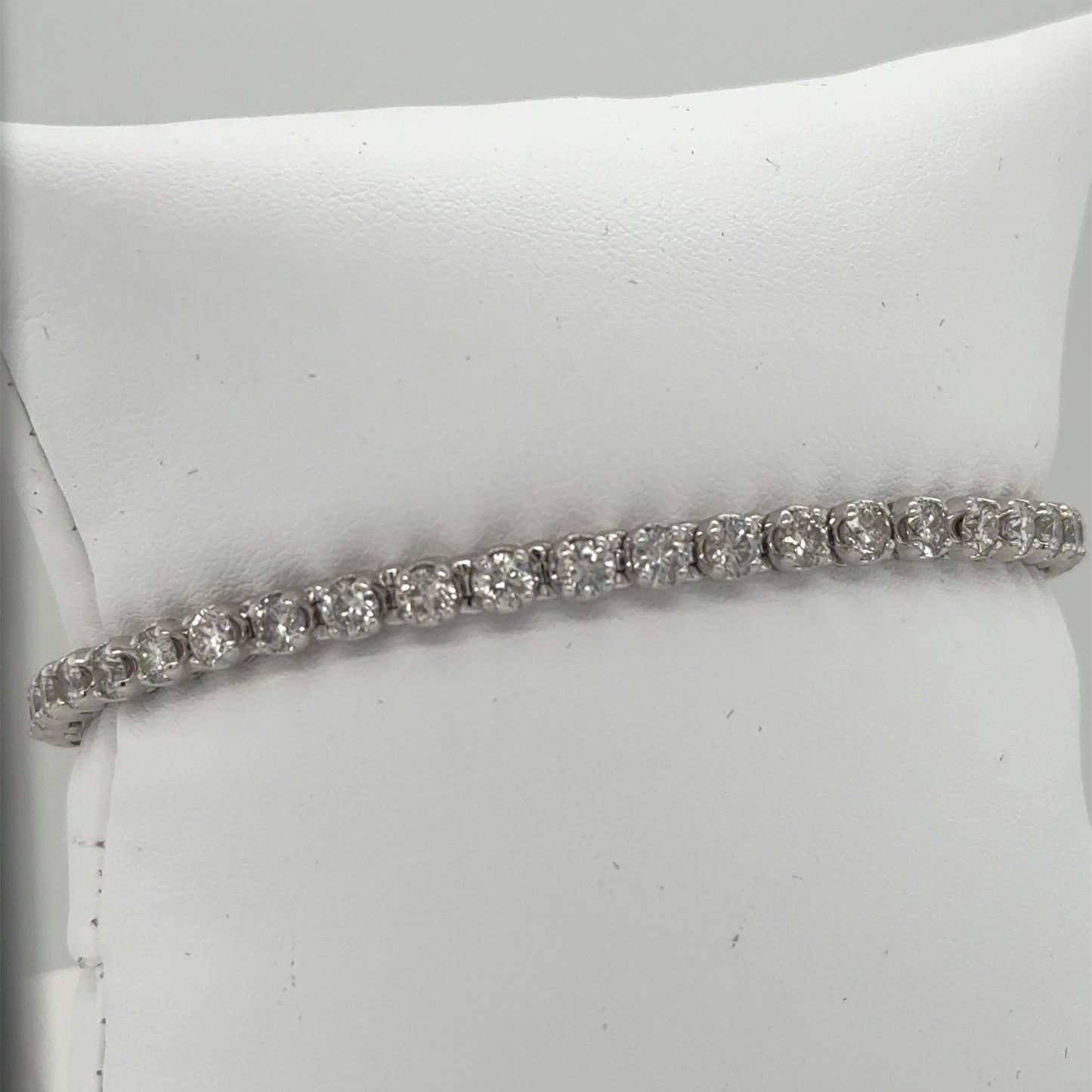 14K white gold tennis bracelet with round diamonds in four-prong settings.