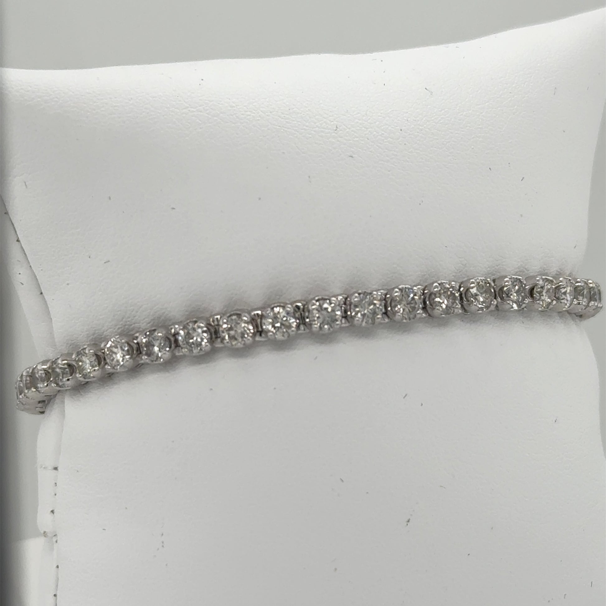 14K white gold tennis bracelet with round diamonds in four-prong settings.
