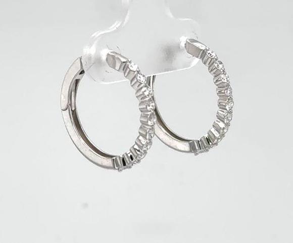 Small 14K white gold diamond hoop earrings with shared prongs and hinged backs.