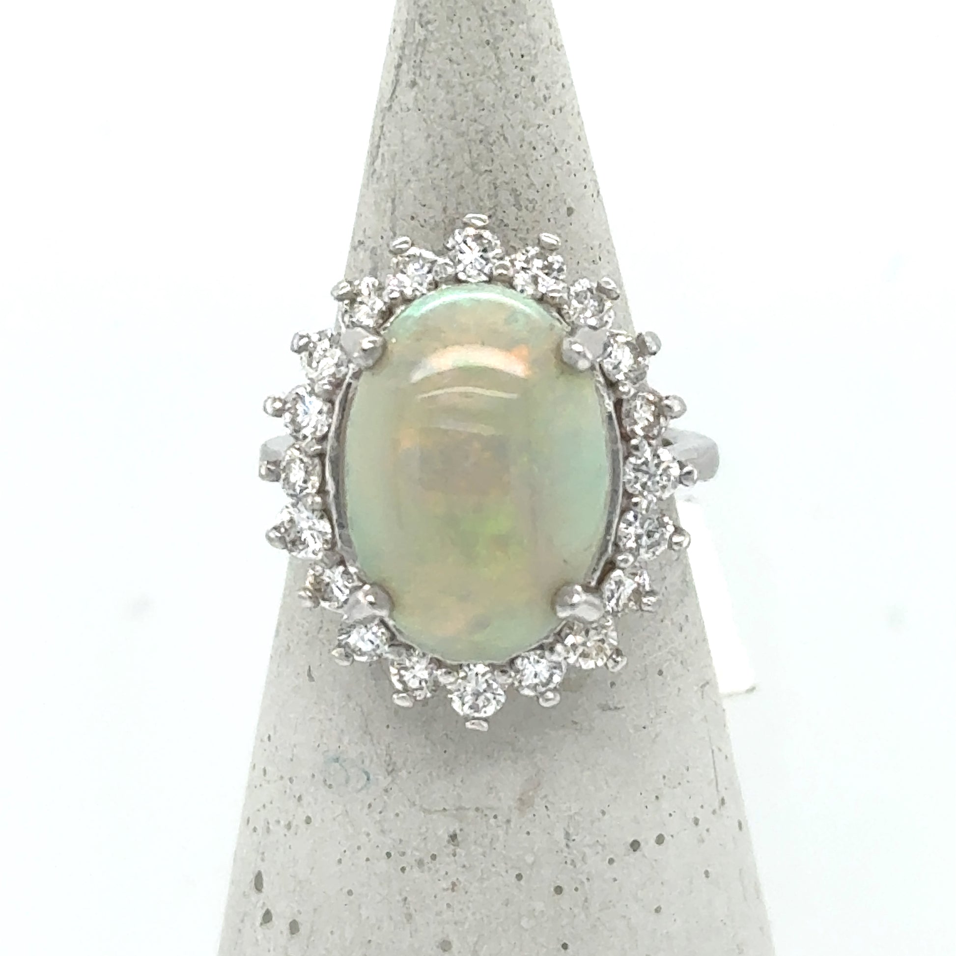 Oval cabochon opal halo ring in 14K white gold with round diamonds.