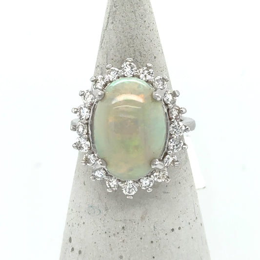 Oval cabochon opal halo ring in 14K white gold with round diamonds.