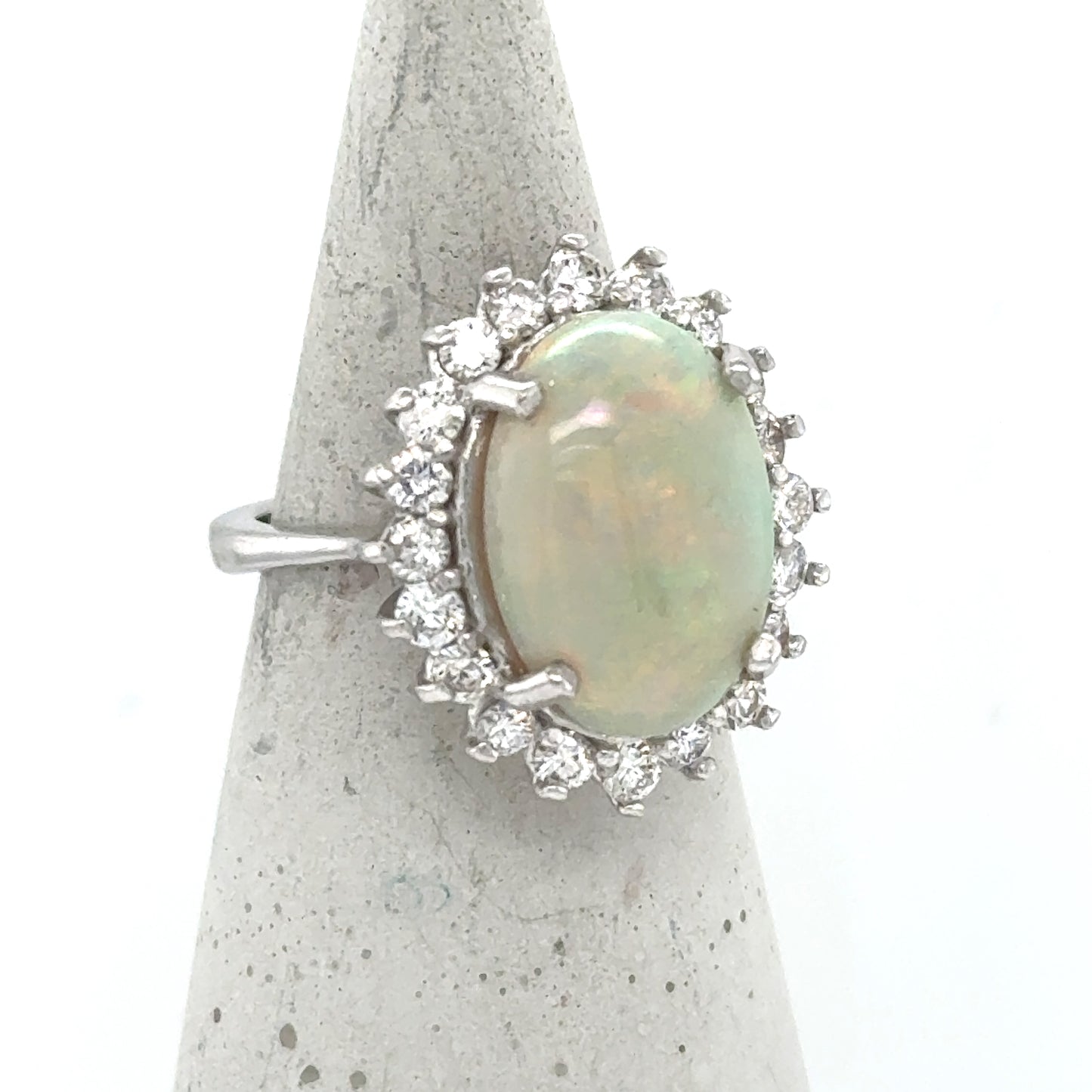 14K white gold ring with oval cabochon opal and diamond halo.