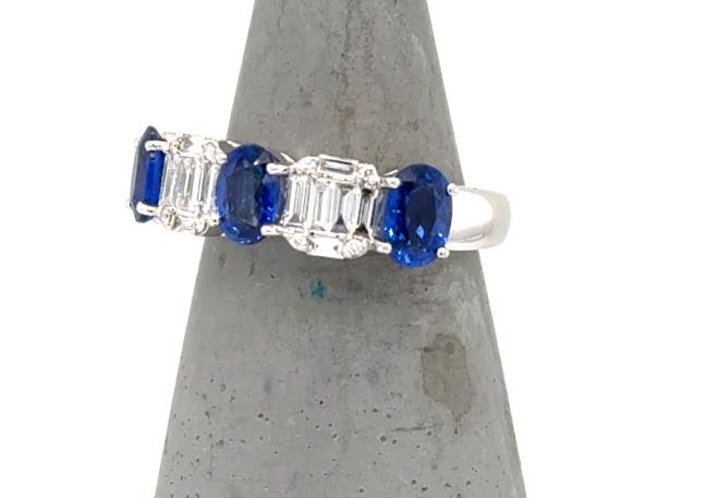 14K white gold band with three oval blue sapphires and baguette diamond clusters.