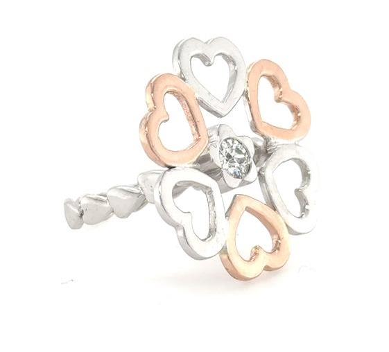 Two-tone white and rose gold open-heart ring with central bezel-set round diamond.