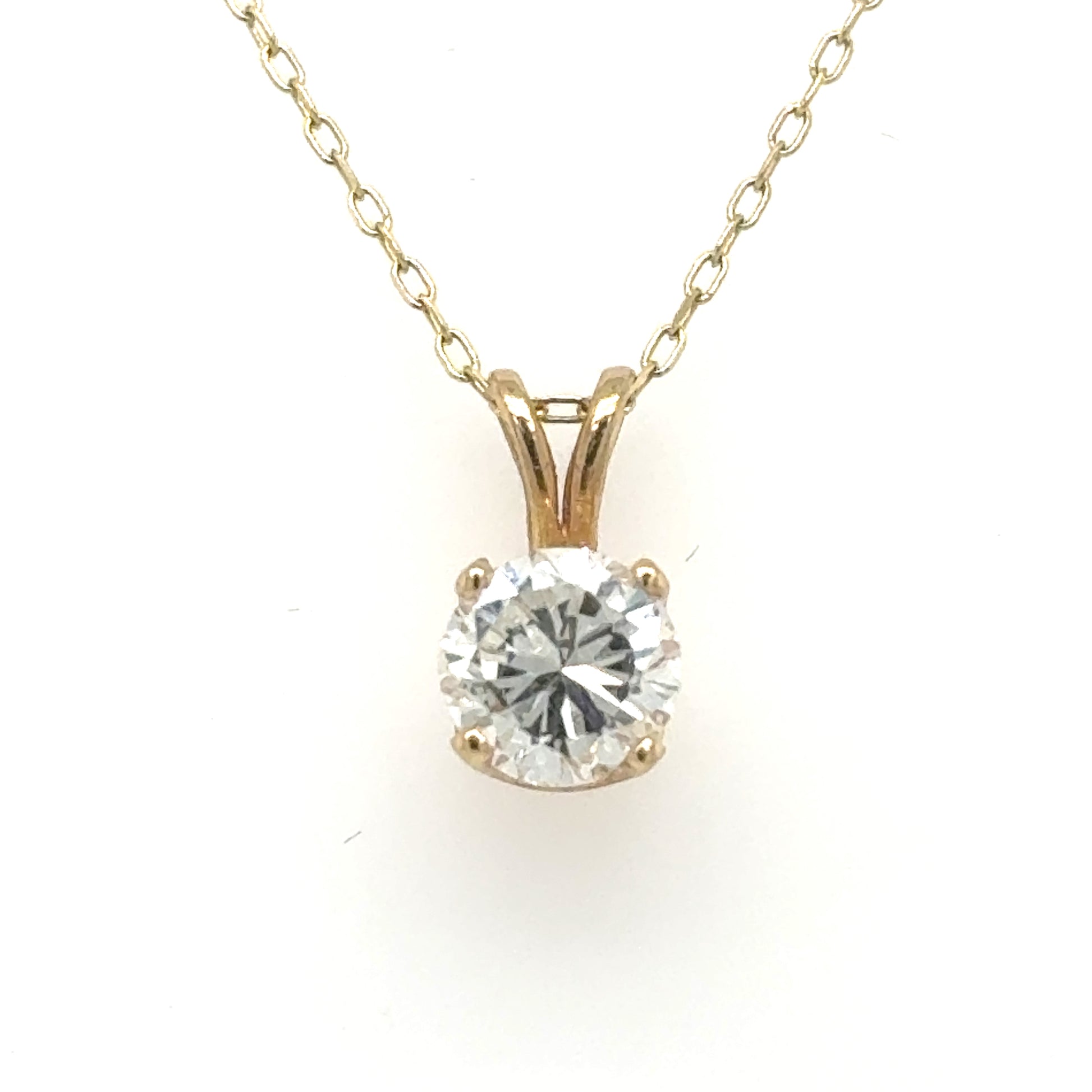 Yellow gold solitaire pendant with round brilliant diamond in four-prong basket and rabbit-ear bail.