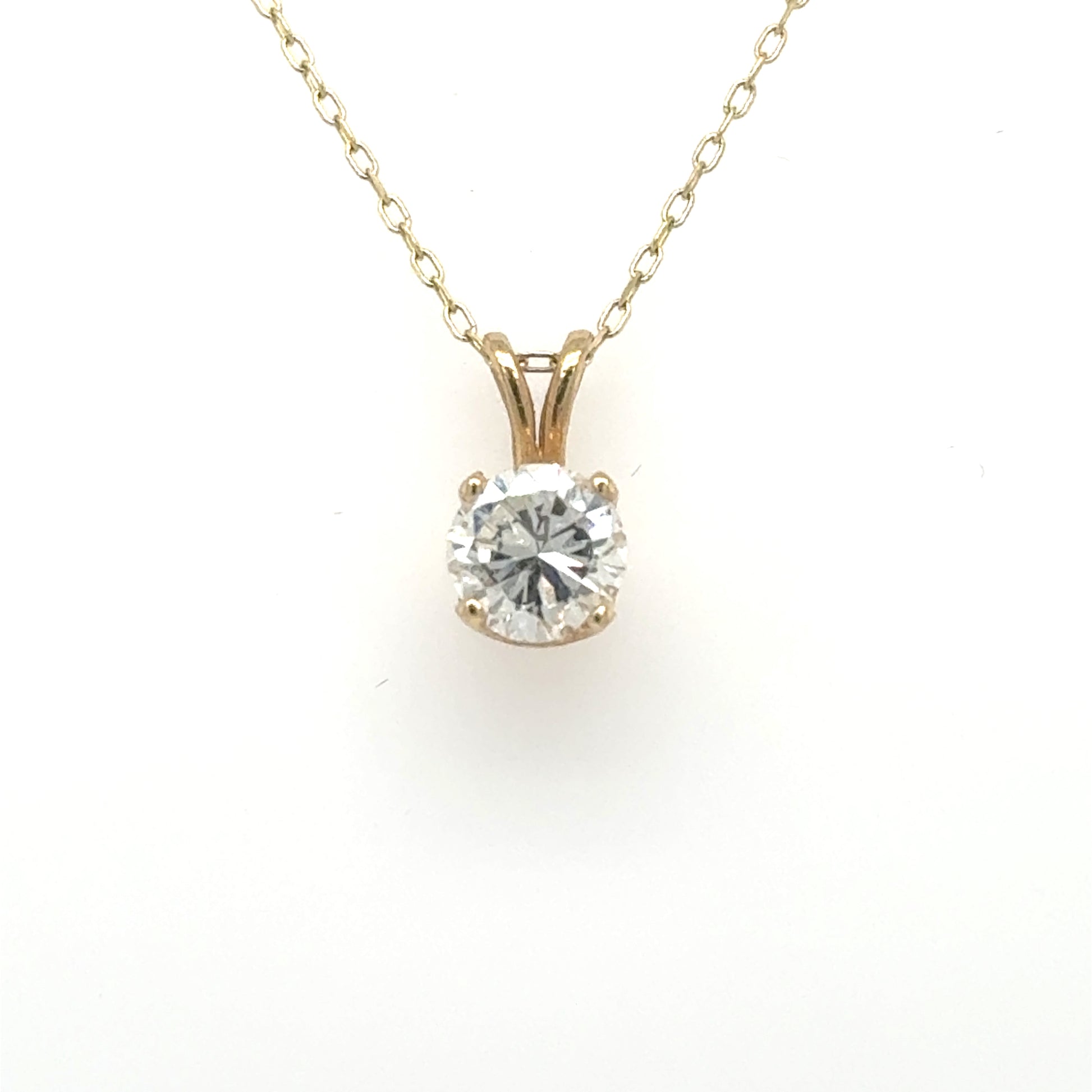Yellow gold solitaire pendant with round diamond in four-prong basket and rabbit-ear bail.