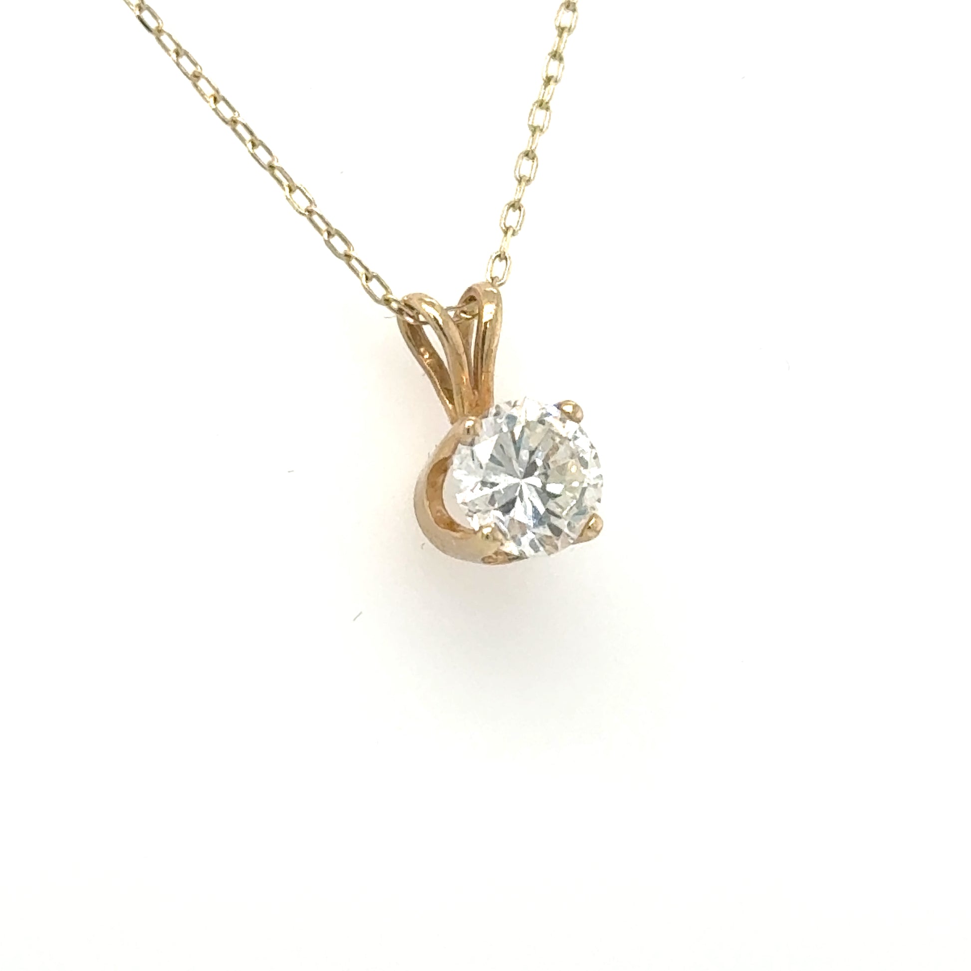 Yellow gold solitaire pendant with round diamond in four-prong basket and rabbit-ear bail.