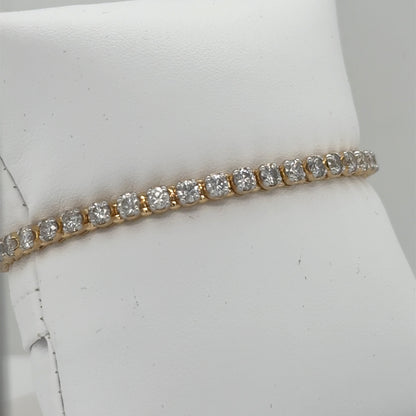 14K yellow gold tennis bracelet with round diamonds in four-prong line settings.