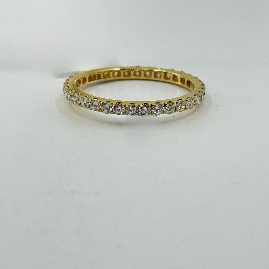 18K yellow gold eternity band with round diamonds in four-prong continuous setting.