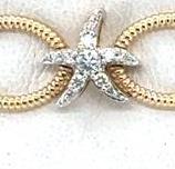 Close-up of a 14K yellow gold link bracelet with a diamond starfish charm.