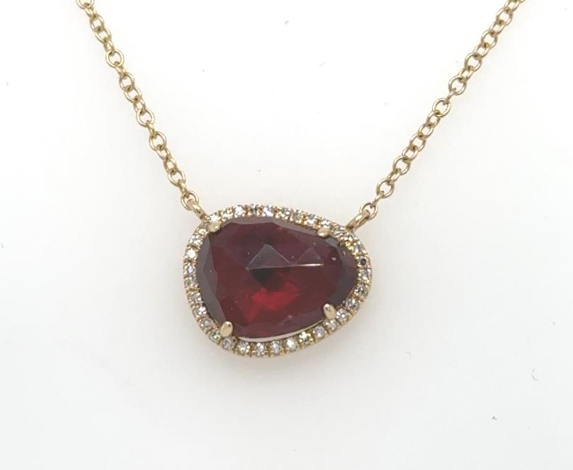 14K yellow gold necklace with asymmetrical red garnet pendant framed by diamond halo.