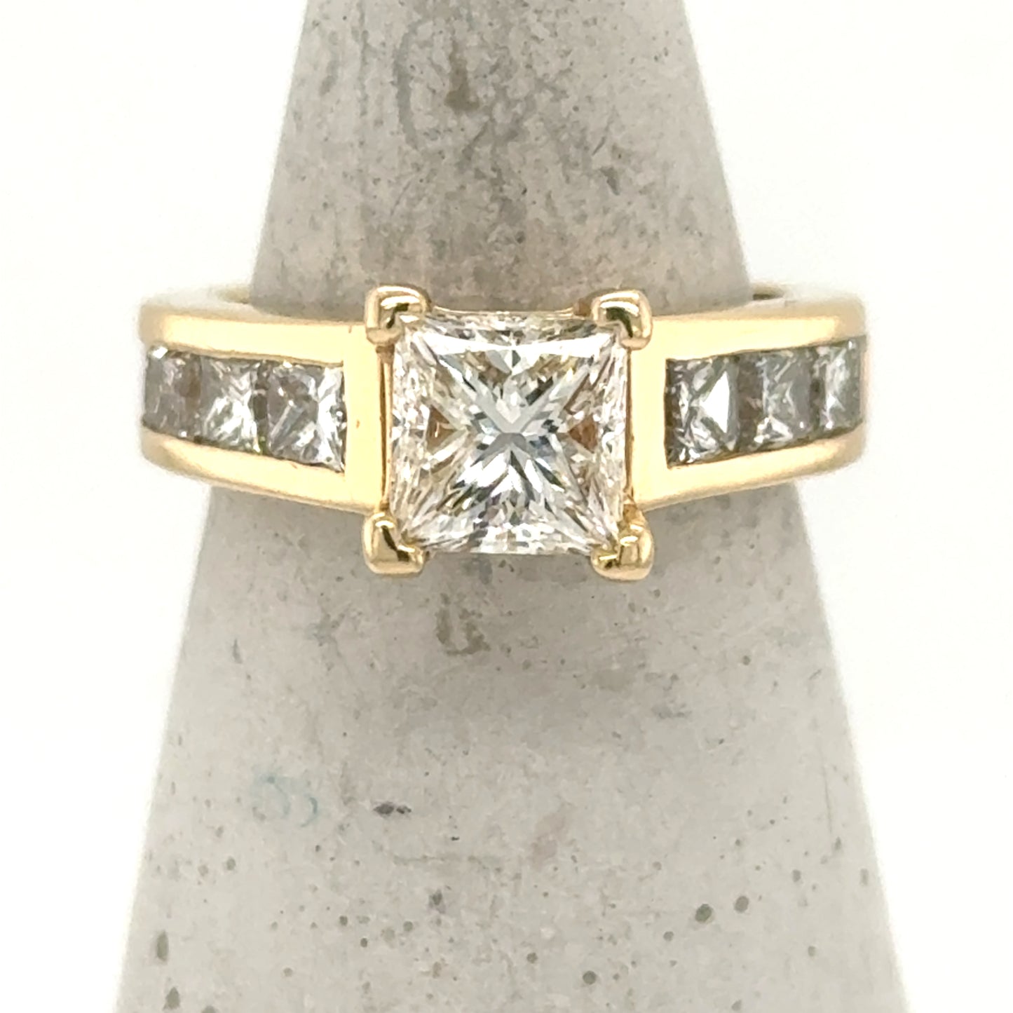 14K yellow gold ring with princess-cut center diamond and channel-set side diamonds.