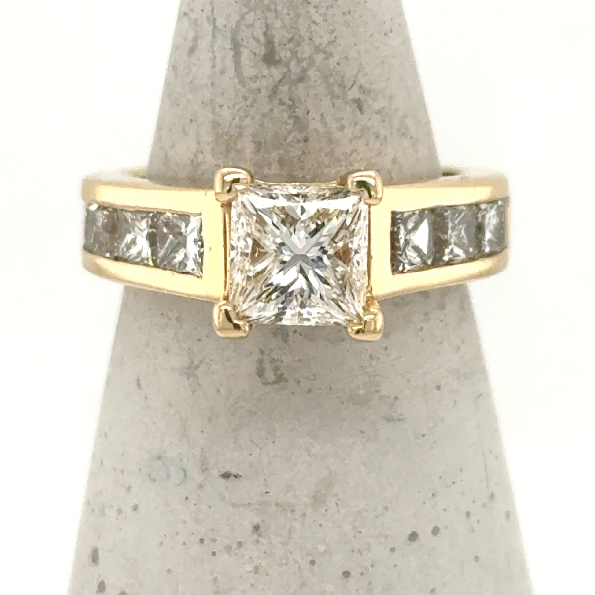 14K yellow gold ring with princess-cut center diamond and channel-set side diamonds.