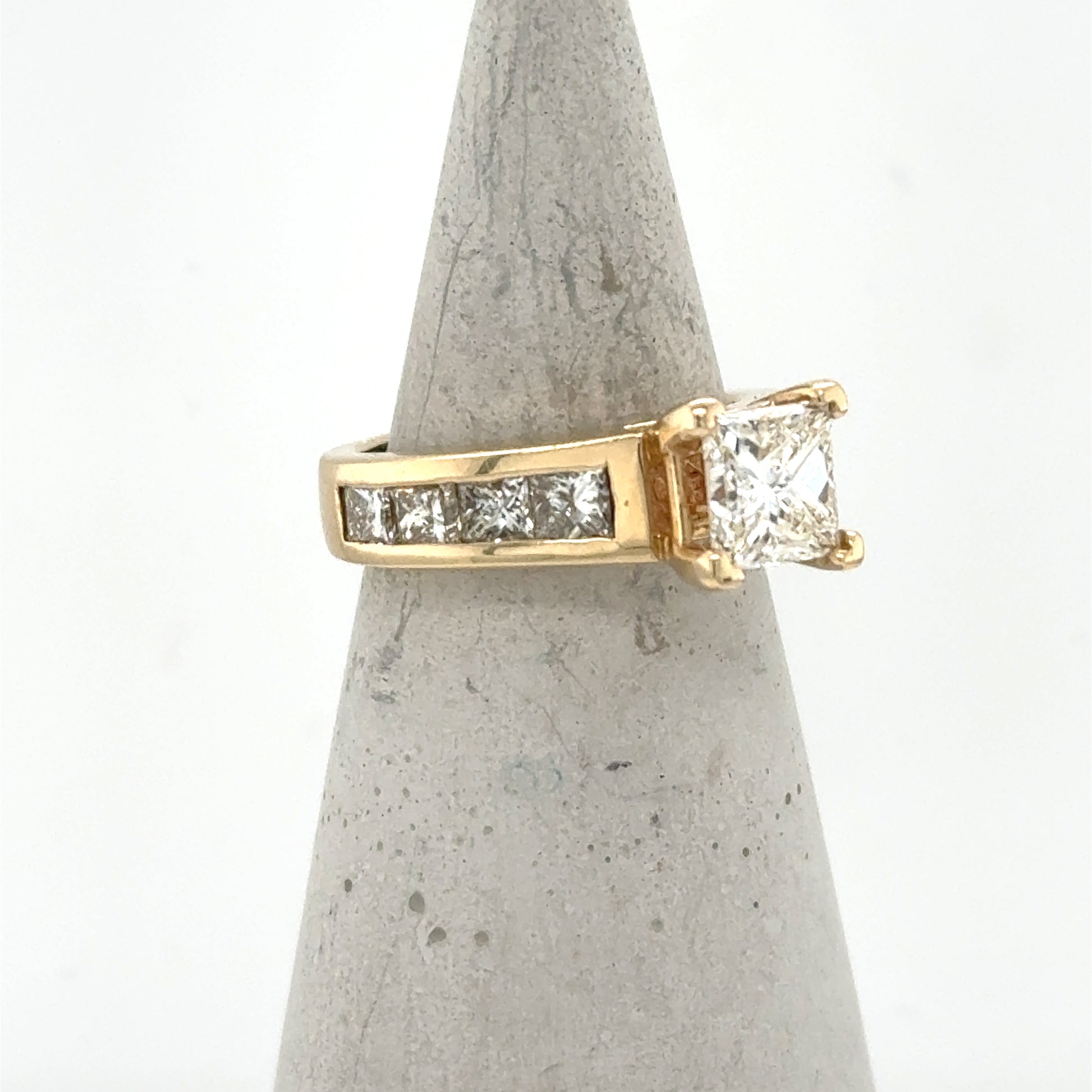 14K yellow gold ring with princess-cut center diamond and channel-set side stones.