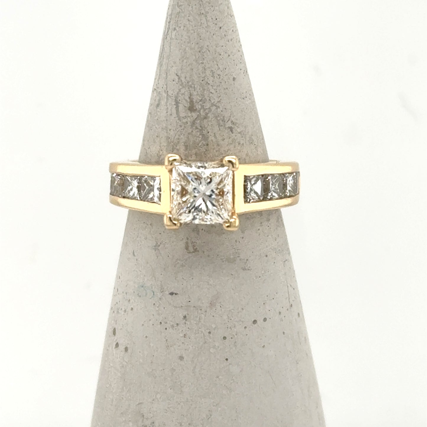 14K yellow gold ring with princess-cut center diamond and channel-set side stones.