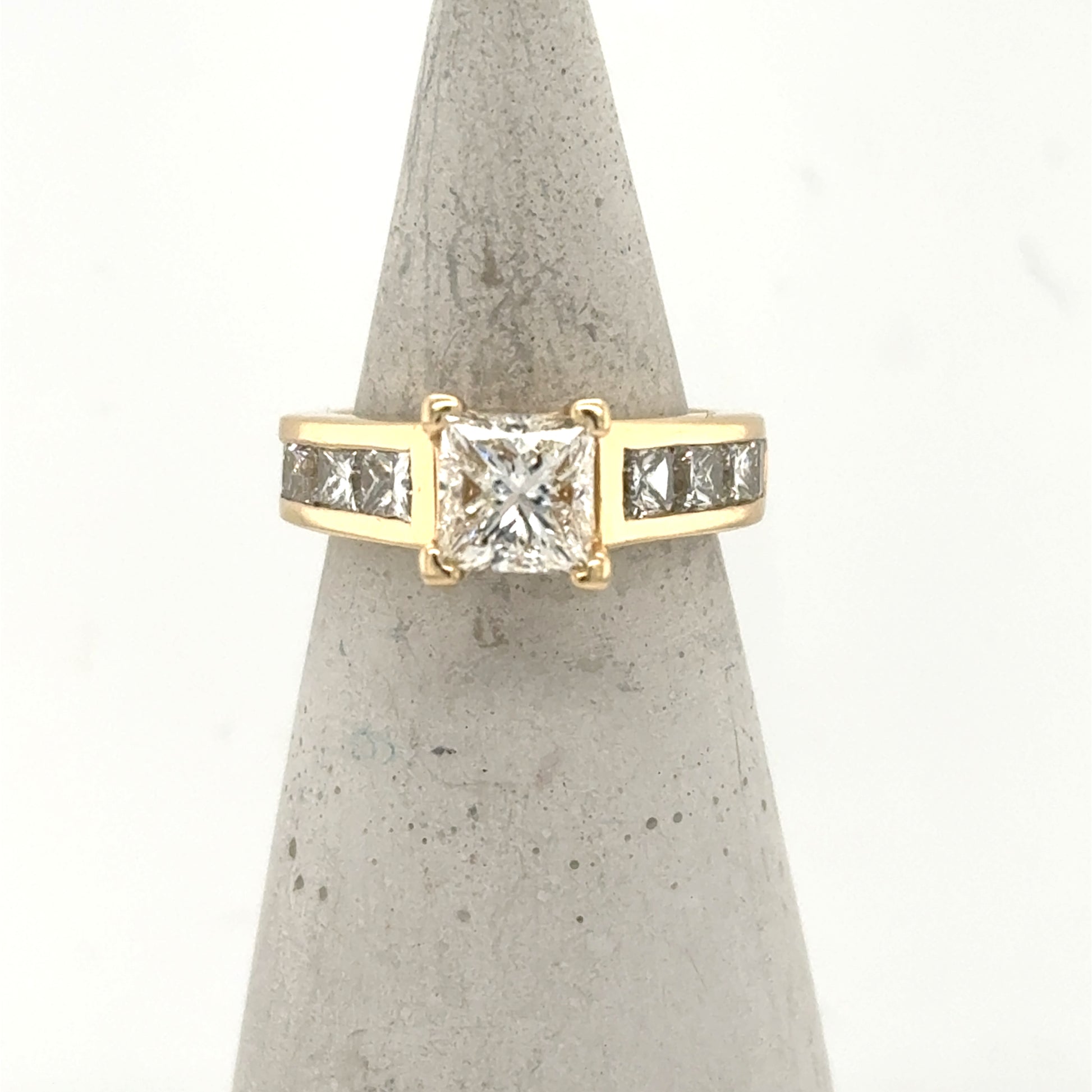 14K yellow gold ring with princess-cut center diamond and channel-set side stones.