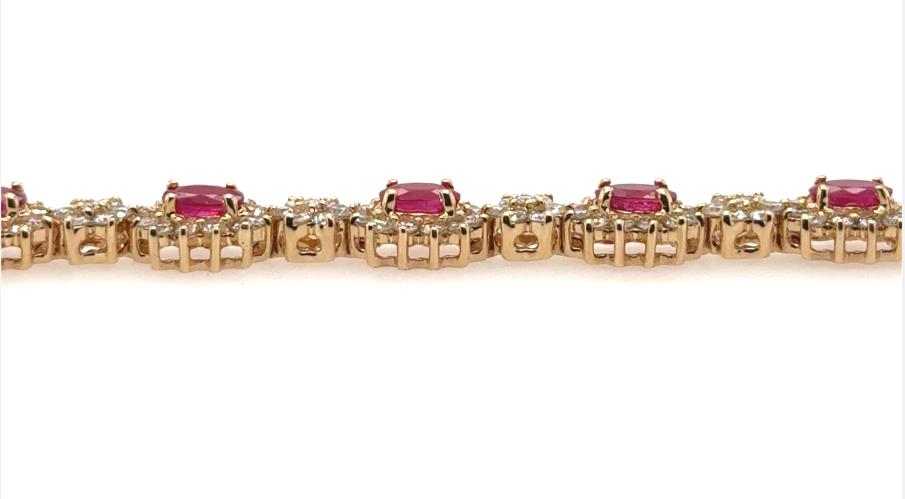 14K yellow gold tennis bracelet with oval rubies haloed by round diamonds.