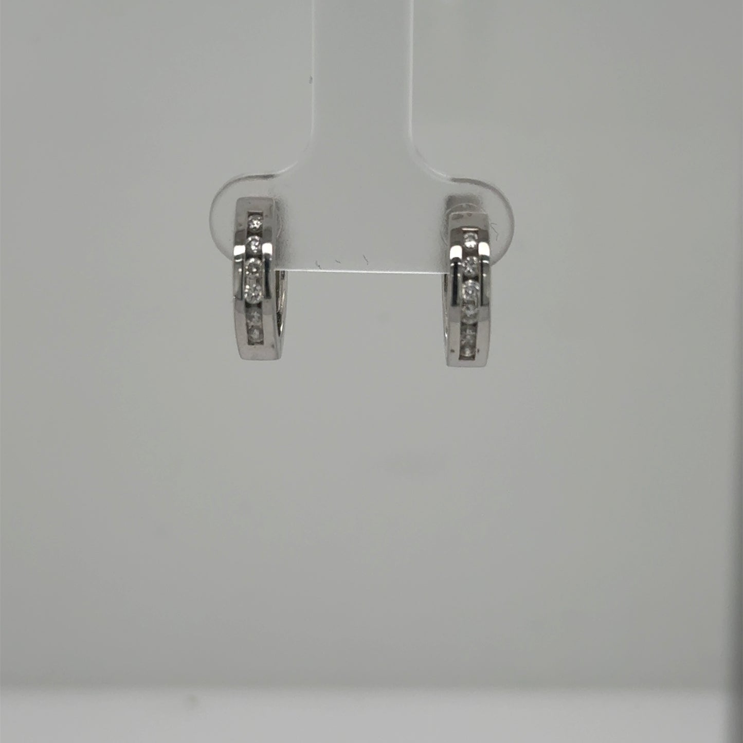 Small 14K white gold huggie hoops with channel‑set round diamonds.