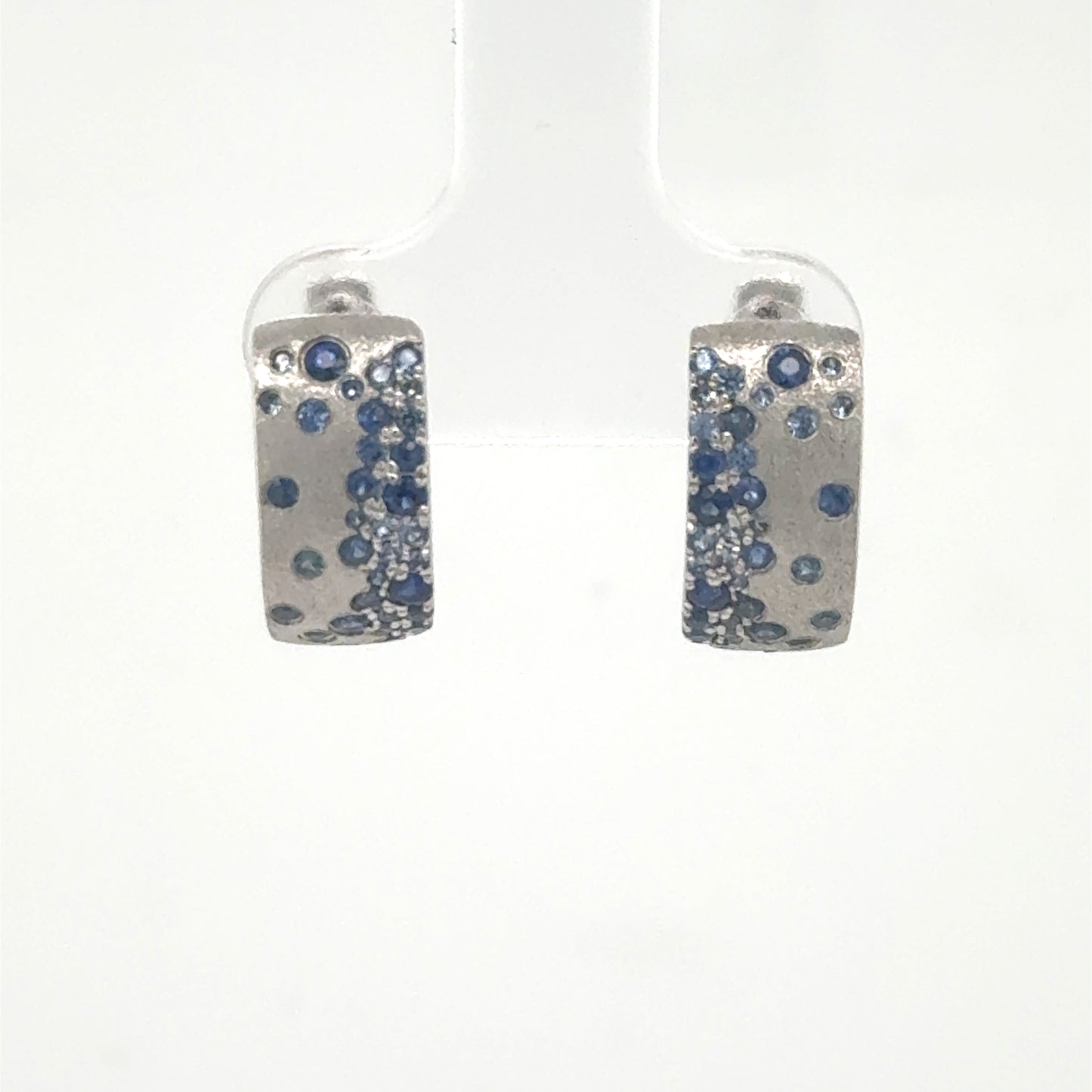 14K white gold huggie hoops with scattered blue sapphire pavé accents.