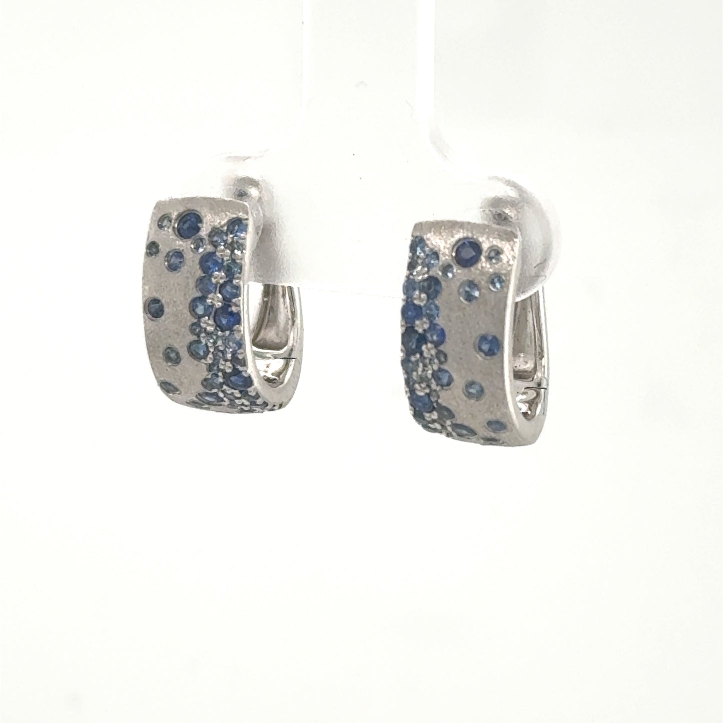 14K white gold huggie hoop earrings with burnished blue sapphire scatter pattern.