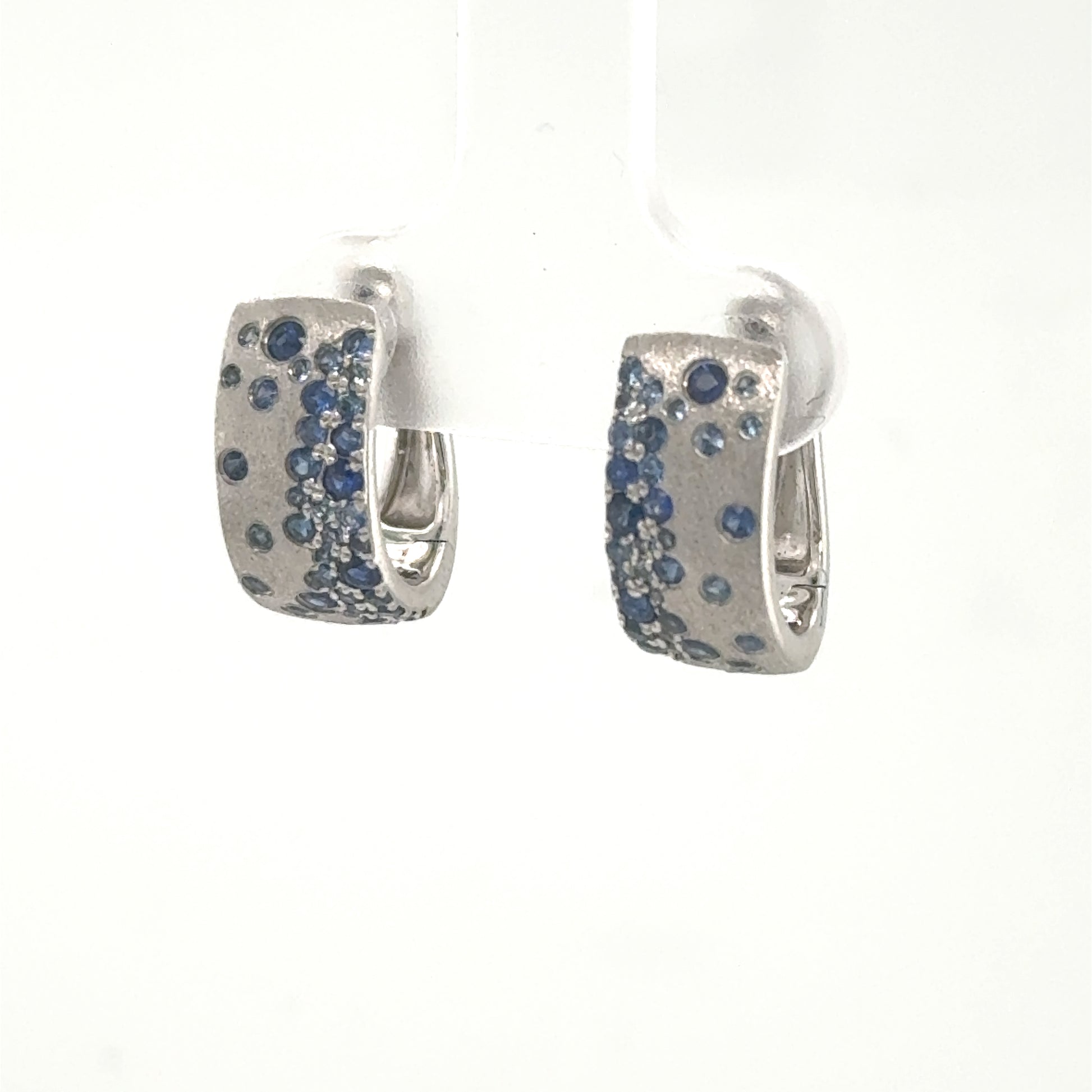 14K white gold huggie hoop earrings with burnished blue sapphire scatter pattern.