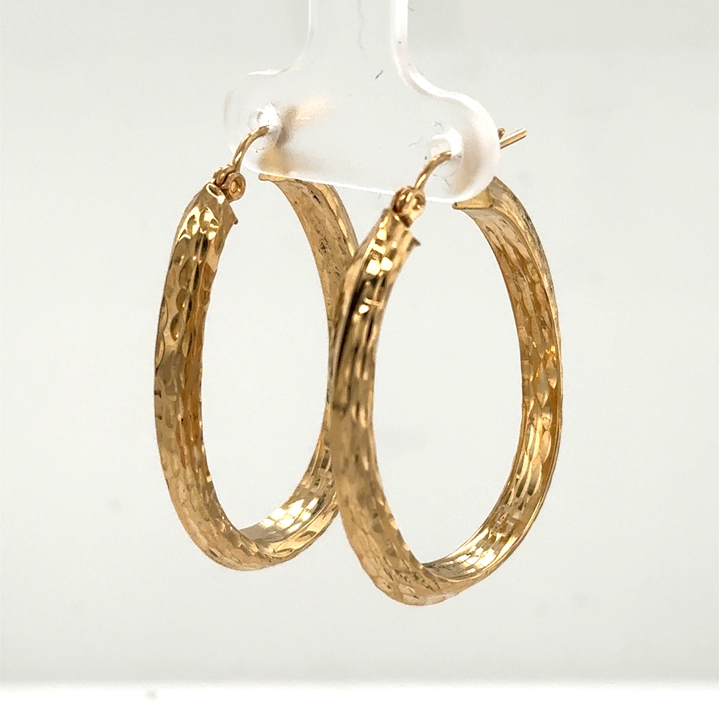 14K yellow gold oval hoop earrings with diamond-cut textured surface for pierced ears.