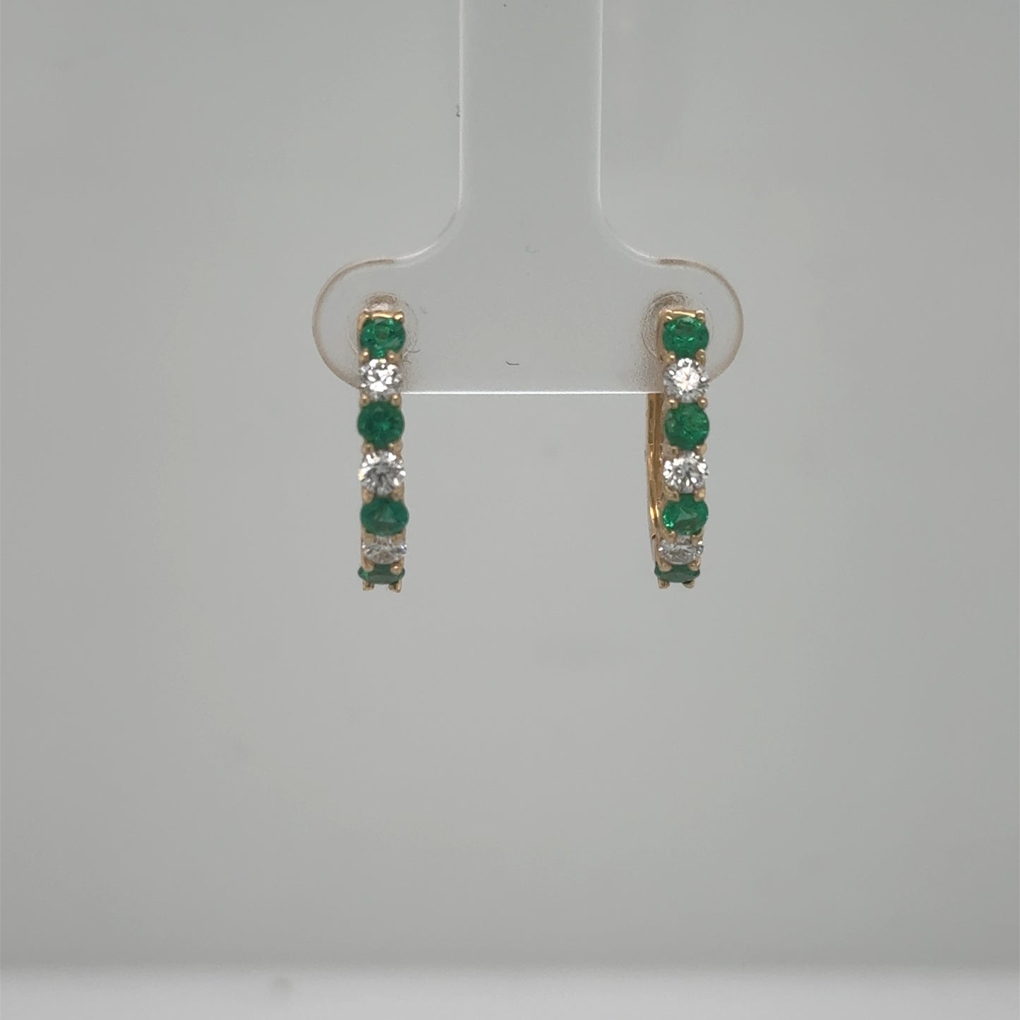 14K yellow gold hoop earrings with alternating round emeralds and diamonds.