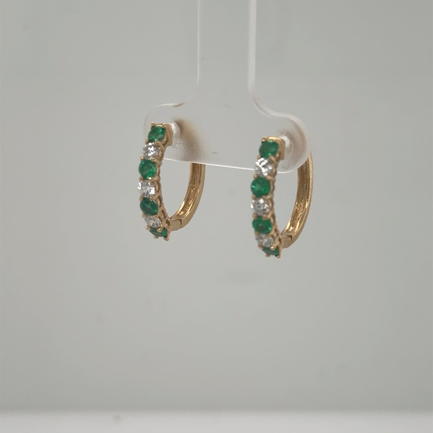 Small 14K yellow gold hoop earrings with alternating round emeralds and diamonds.