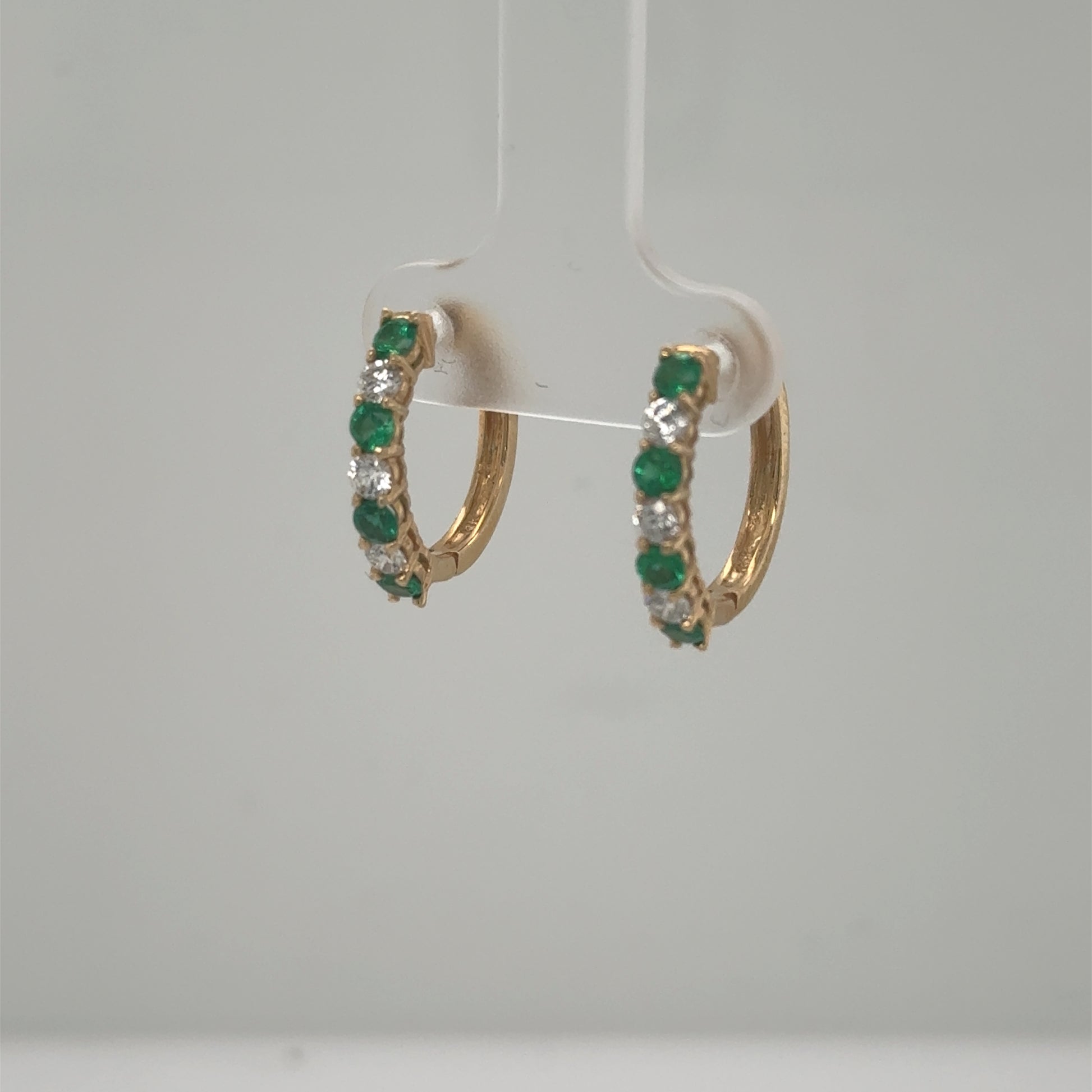Small 14K yellow gold hoop earrings with alternating round emeralds and diamonds.