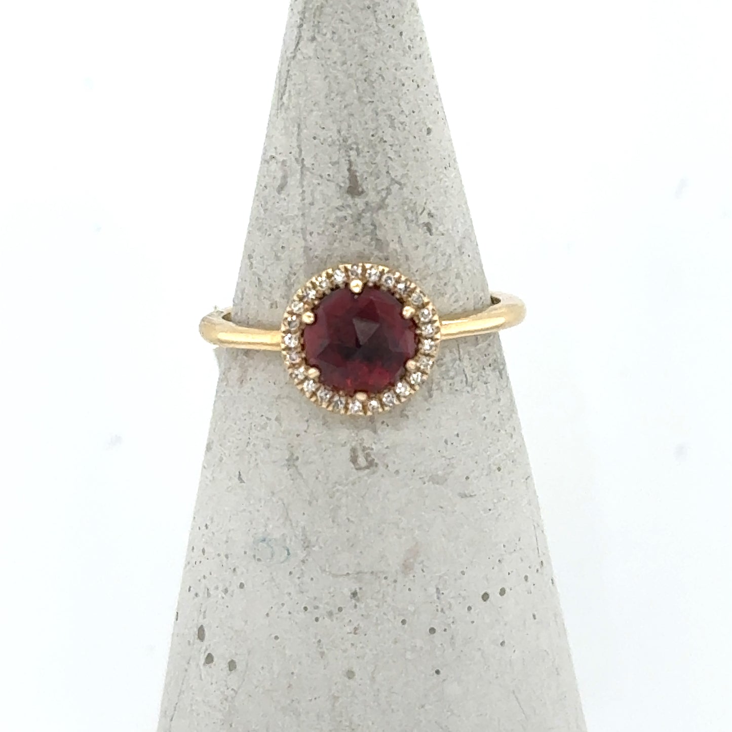 Yellow gold ring with round red garnet and diamond halo on slim band.
